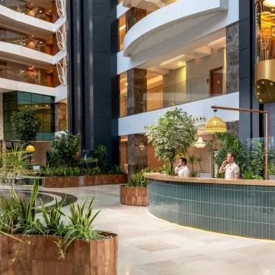 Une réception d'hôtel luxueuse et végétalisée, avec un comptoir de réception.