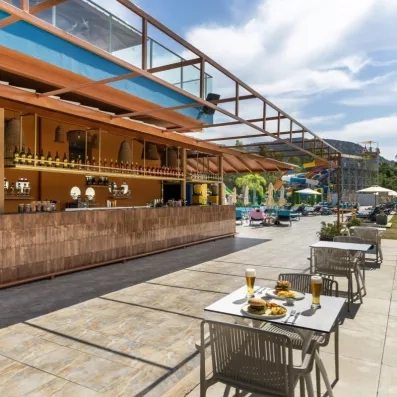 Un snack-bar extérieur situé au bord d'une piscine face à un parc aquatique.