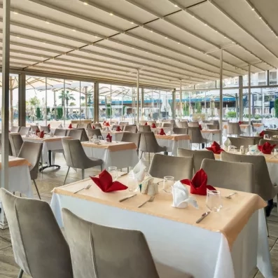 Une vaste salle de réception sous une structure couverte, avec de nombreuses tables prêtes.