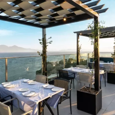 Une terrasse de restaurant protégée par une pergola, offrant une vue sur l'horizon.