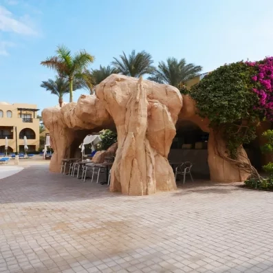 Terrasse ombragée dans une structure rocheuse atypique au cœur des jardins tropicaux de l'hôtel à Hurghada.