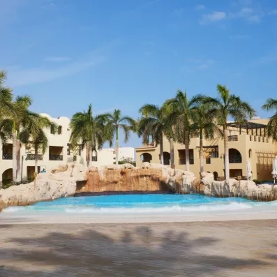 Piscine à vagues artificielle avec cascade et palmiers au Mondi Club Stella Garden, complexe hôtelier à Hurghada, Égypte.