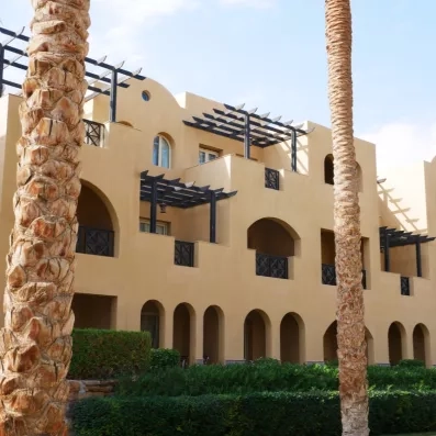 Bâtiments de l'hôtel avec arches et palmiers sous le soleil au Mondi Club Stella Garden en Égypte.