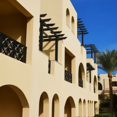 Architecture orientale aux façades ocre et balcons avec pergolas au Mondi Club Stella Garden, Hurghada, Égypte.