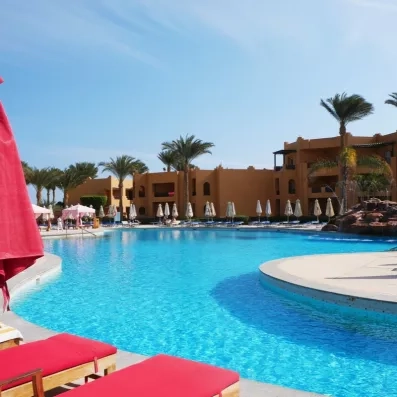 Piscine extérieure azur entourée de transats rouges et palmiers au Stella Beach Resort, Hurghada en Égypte.