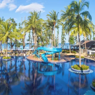 Une piscine entourée de grands palmiers, sous un soleil bleu.