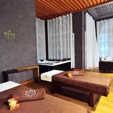 Deux tables de massage au spa de l'hôtel avec un jacuzzi au fond  