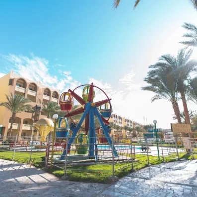 petite roue enfant dans le jardin à côté de la petite piscine, soleil, palmier, bâtiment de l'hôtel