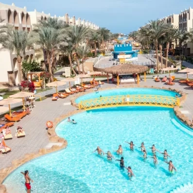 grande piscine extérieur avec pont au milieu, transats, parasol, palmier, animation aquagym 