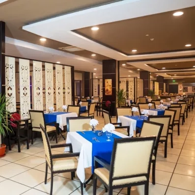 grande salle du restaurant de l'hôtel, chaises et tables dressées, plantes décoratives 