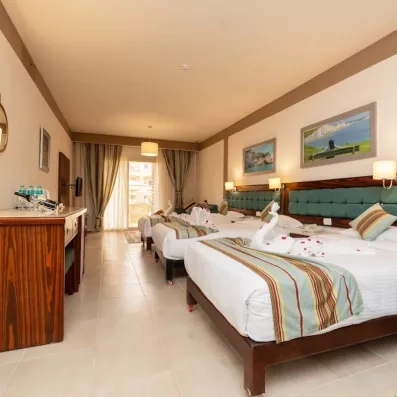 chambre avec trois lits, coiffeuse, tableaux décoratifs Tv, porte fenêtre 