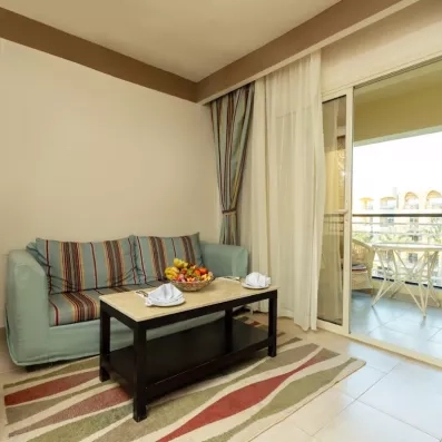 Canapé deux places dans la chambre, avec petite table basse, porte fenêtre avec terrasse avec table et chaise 