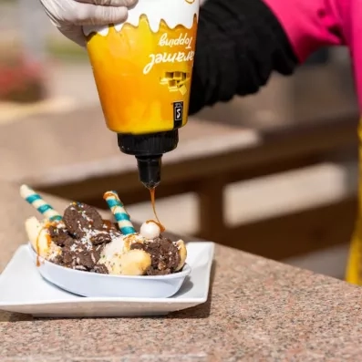 chef mettant de la crème caramel sur un dessert avec des bananes 
