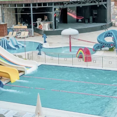 Un espace aquatique extérieur avec une piscine et un bassin pour enfants avec des toboggans.