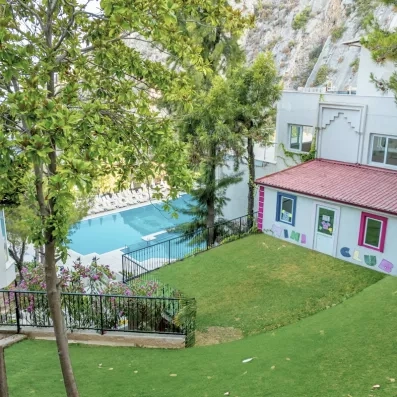 Une vue en surplomb montrant un jardin verdoyant, un mini Club et une piscine.