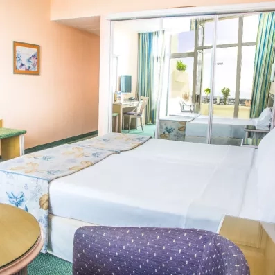 Une vue d'angle d'une chambre montrant le lit et le mobilier en bois clair.