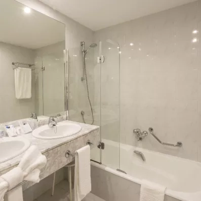 Une salle de bain moderne et propre équipée d'une baignoire et d'un grand miroir.