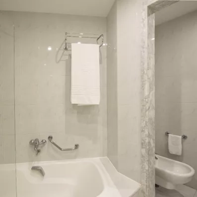 Un zoom sur la baignoire blanche carrelée dans une salle de bain aux tons neutres.