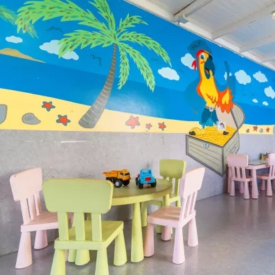 Un espace de jeux intérieur pour enfants avec des petites tables et chaises colorées.