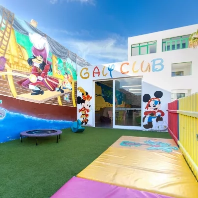 Une cour extérieure en pelouse et avec des décorations menant au miniclub.