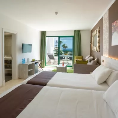 La vue depuis les lits montre l'agencement de la chambre avec sa télévision mural et l'accès direct au balcon.