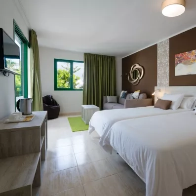 Une chambre spacieuse et lumineuse propose deux lits simples et un petit coin salon.