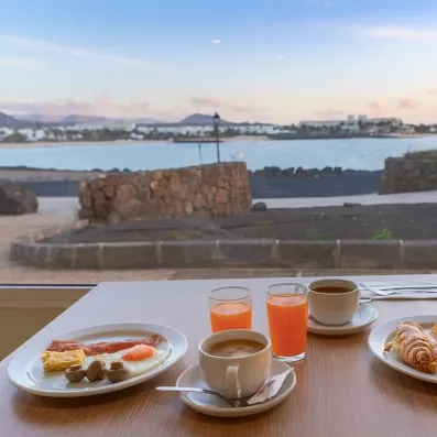 Un petit-déjeuner complet servi en terrasse avec une vue sur la mer et la côte.
