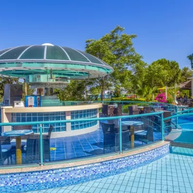 Un bar circulaire moderne, situé au bord de l'eau sous un dôme turquoise.