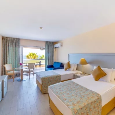 Une chambre spacieuse avec deux lits simples et une large baie vitrée ouvrant sur un balcon.