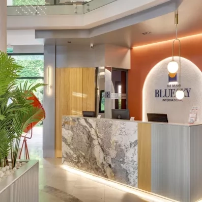 Le comptoir de réception moderne, mêlant marbre, bois chaleureux et éclairage design.