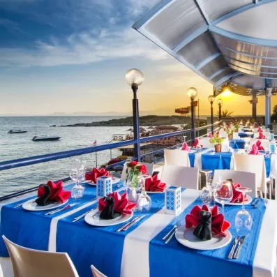 Des tables de restaurant dressée pour le dîner sur une jetée, au coucher du soleil.