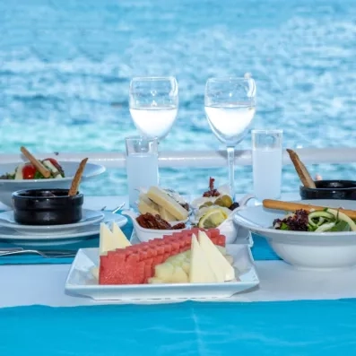 Une table dressée face à la mer avec des plats typiques grecs et turcs et des fruits.
