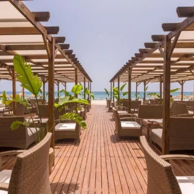 Espace lounge en bois face à la mer, avec fauteuils ombragés