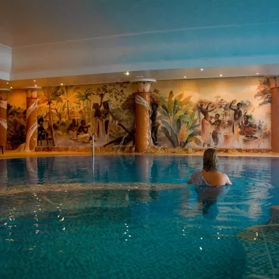 Piscine intérieure décorée de fresques colorées, avec personne profitant de l’eau