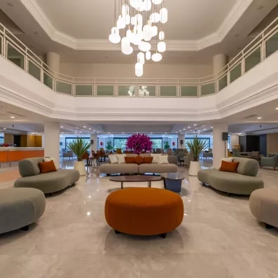 Un hall d'entrée central baigné de lumière, avec un lustre monumental surplombant.