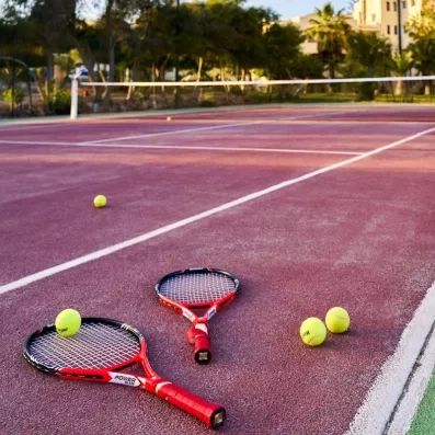 Terrain de tennis en plein air avec raquettes et balles disponible à l'hôtel Les Quatre Saisons.