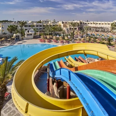 Grand parc aquatique avec toboggans colorés et piscine extérieure sous le soleil de l'hôtel à Djerba.