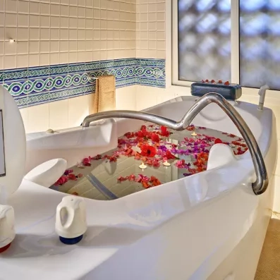 Bain bouillonnant relaxant parsemé de fleurs et bougies au spa de l'hôtel Les Quatre Saisons Djerba.