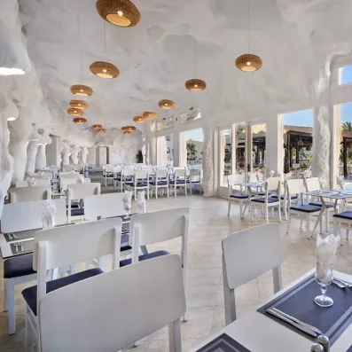 Salle de restaurant lumineuse au design troglodyte avec mobilier blanc moderne à l'hôtel Les Quatre Saisons.