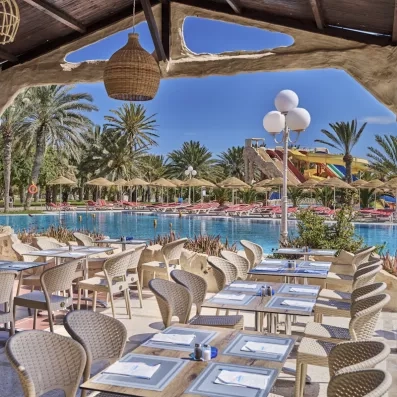 Terrasse ombragée du restaurant offrant une vue imprenable sur la piscine et les toboggans du parc aquatique.