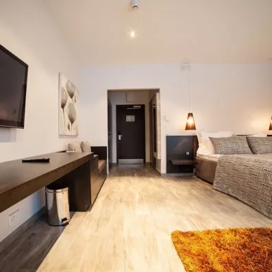 Chambre de l'hôtel avec grand lit deux places, coiffeuse, TV, coin repos, confortable