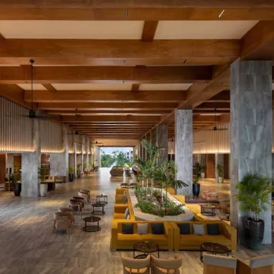 lobby, canapés jaunes, plafond colonial en bois, plantes au centre de la pièce