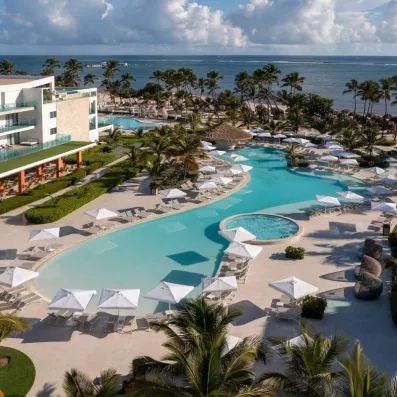 piscine près de la plage, pieds dans l'eau, palmiers et végétation importante, transats et parasols