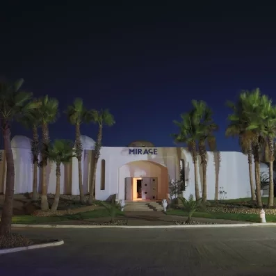 Entrée de la discothèque Le Mirage illuminée de nuit sous les palmiers au Djerba Golf Resort.
