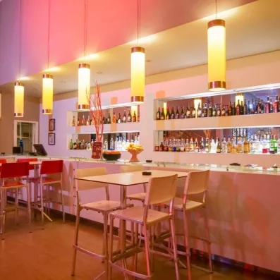 Comptoir du bar américain illuminé proposant une large sélection de boissons et spiritueux à l'hôtel.