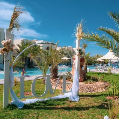 Jardin ensoleillé avec piscine, palmiers et décor romantique au complexe hôtelier César Thalasso à Djerba.