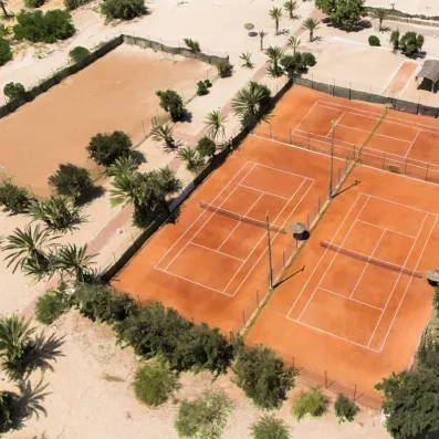 Vue aérienne des terrains de tennis en terre battue au milieu des jardins de l'hôtel à Djerba.