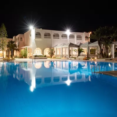 Piscine illuminée de nuit à l’hôtel Djerba Golf Resort & Spa, destination de vacances relaxantes en Tunisie.