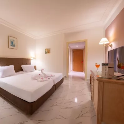 Intérieur lumineux d'une chambre d'hôtel à Djerba avec vue sur le mobilier en bois et télévision.