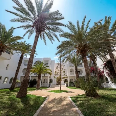 Jardins luxuriants et palmiers entourant l'architecture blanche typique du Djerba Golf Resort en Tunisie